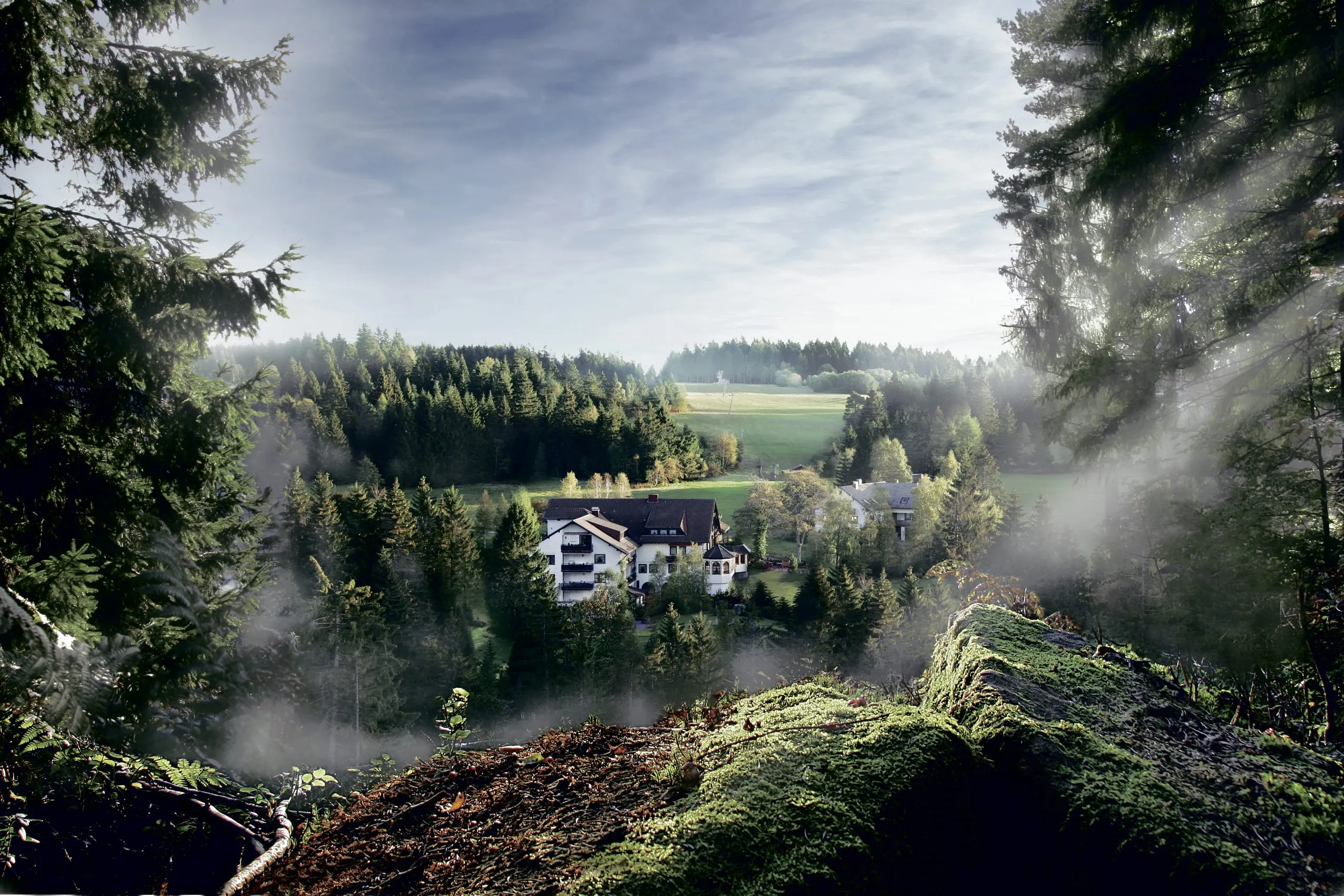 Au&szlig;enansicht auf das Hotel Waldblick Kniebis mit umliegenden H&uuml;geln des Schwarzwaldes
