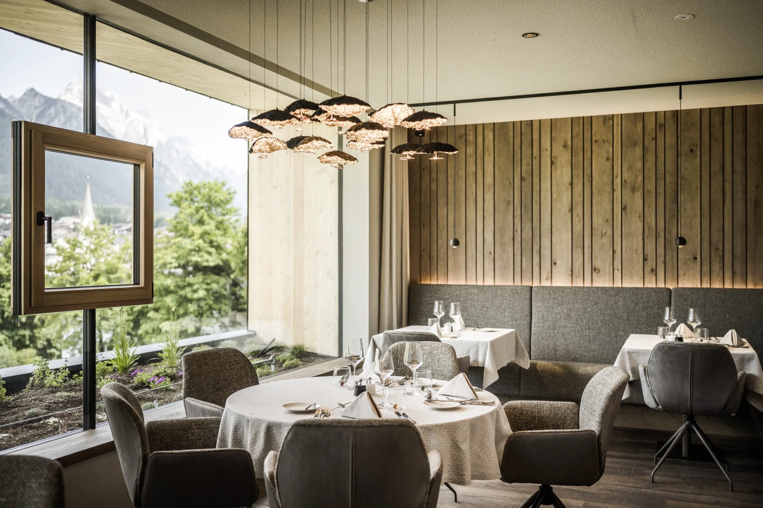 Restaurant im Excelsior Dolomites Life Resort mit Designerleuchte und Fenster im Fenster