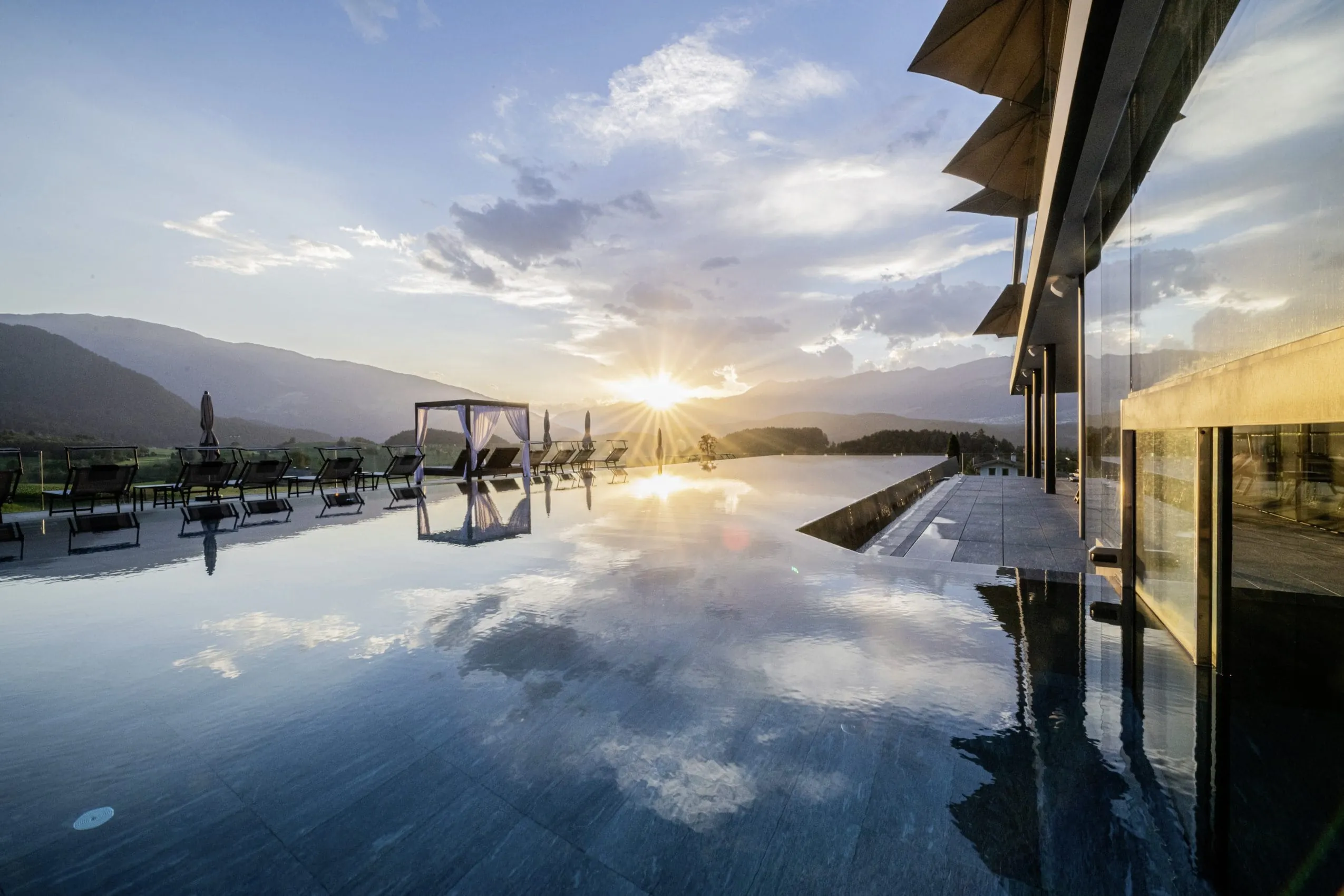 Outdoorpool im Hotel Winkler mit Daybed mit weißen Vorhängen in der Abendsonne