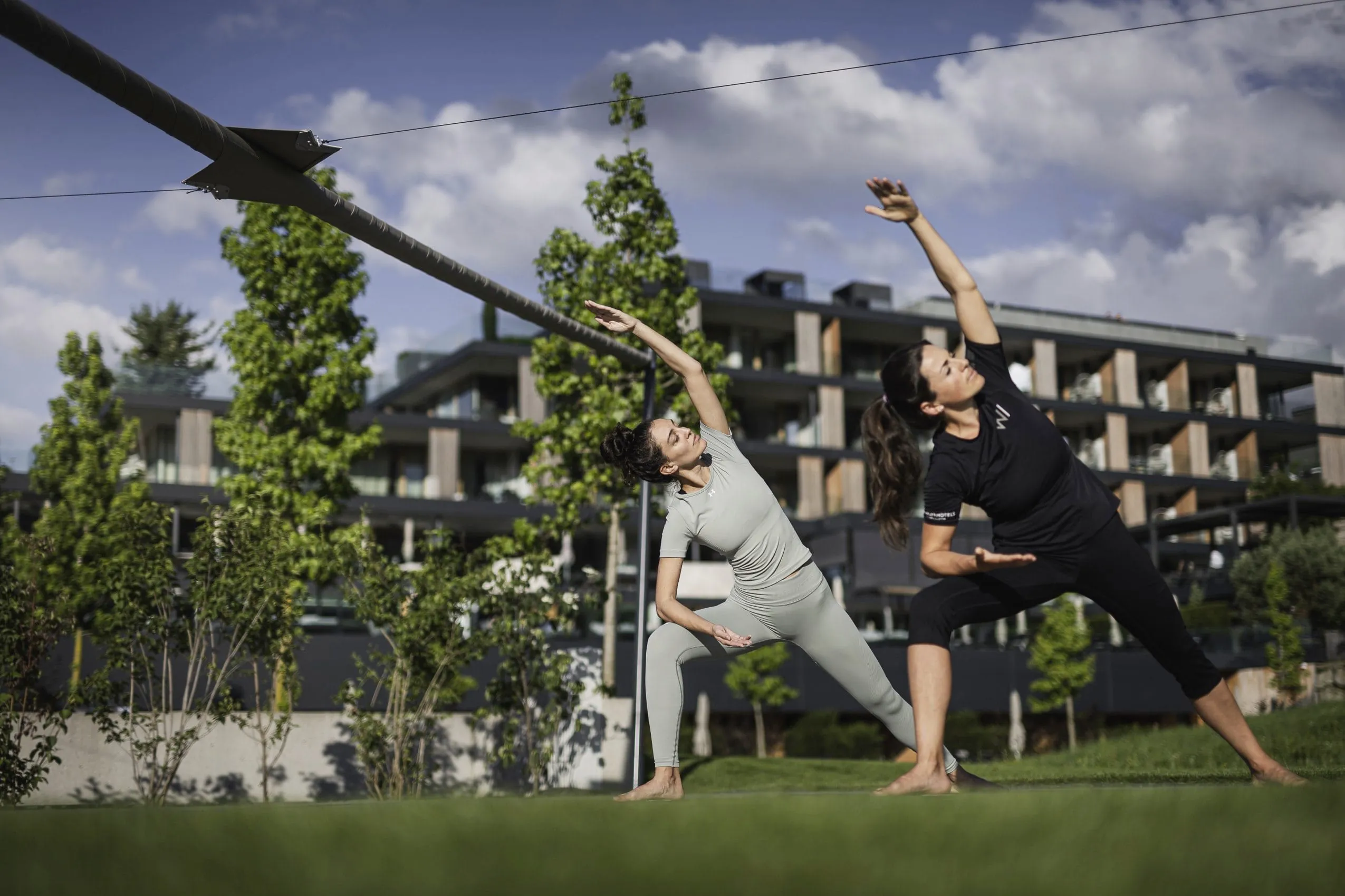zwei Frauen machen Yoga auf der Wiese vor dem Hotel Winkler