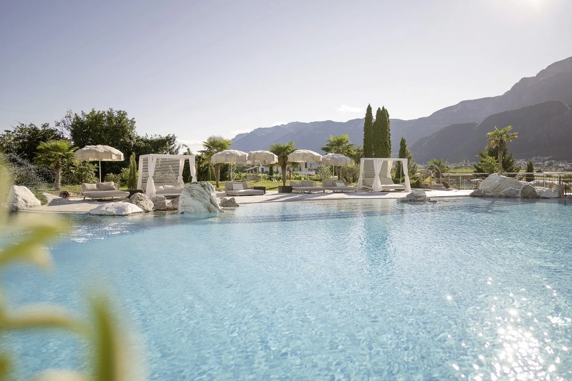 Outdoorpool des Weinegg Wellviva Resort mit Felsen am Rand und weißen Sonnenschirmen