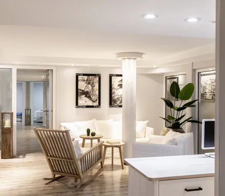 Blick in den Spabereich des Beach Motel St. Peter-Ording mit Holz-Schaukelstuhl, gemütlichem, weißen Sofa und schwarz-weiß Bildern an der Wand