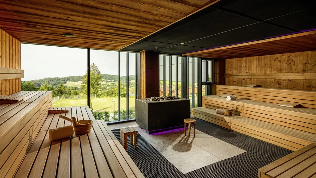 Blick in die große Sauna des Angerhof Sport- & Wellnesshotels mit Panoramafenstern und weitläufigem Blick in die Natur