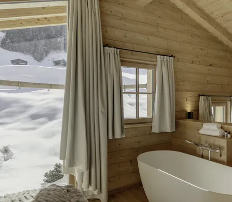 Freistehende Badewanne in einem der Hygna Chalets und Blick auf die Schneelandschaft