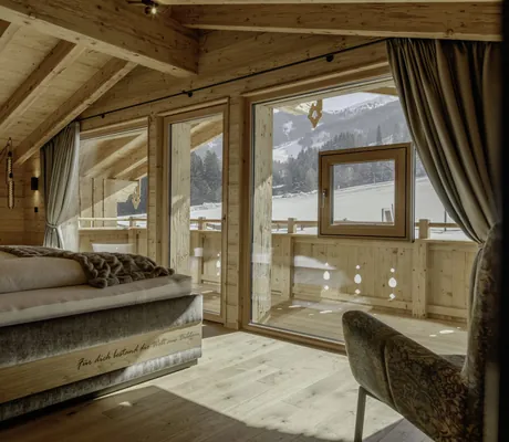 Ein Zimmer mit einem Doppelbett und einem Sessel in einem Chalet der Hygna Chalets und Blick auf die Winterlandschaft