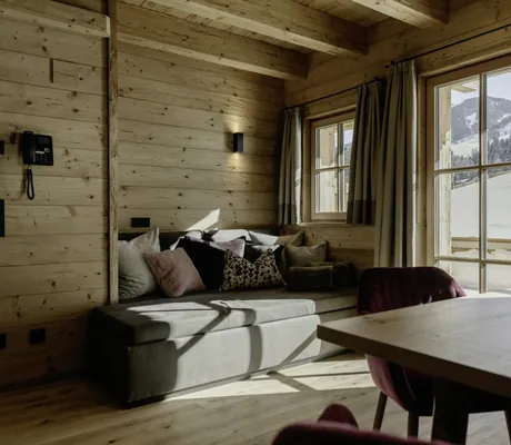 Gemütliches graues Sofa mit vielen Kissen und Holzwänden in den Hygna Chalets