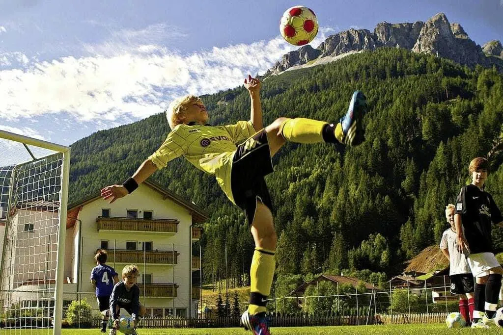 Junge macht Fallrückzieher in gelbem Trikot im Hotel Alpin