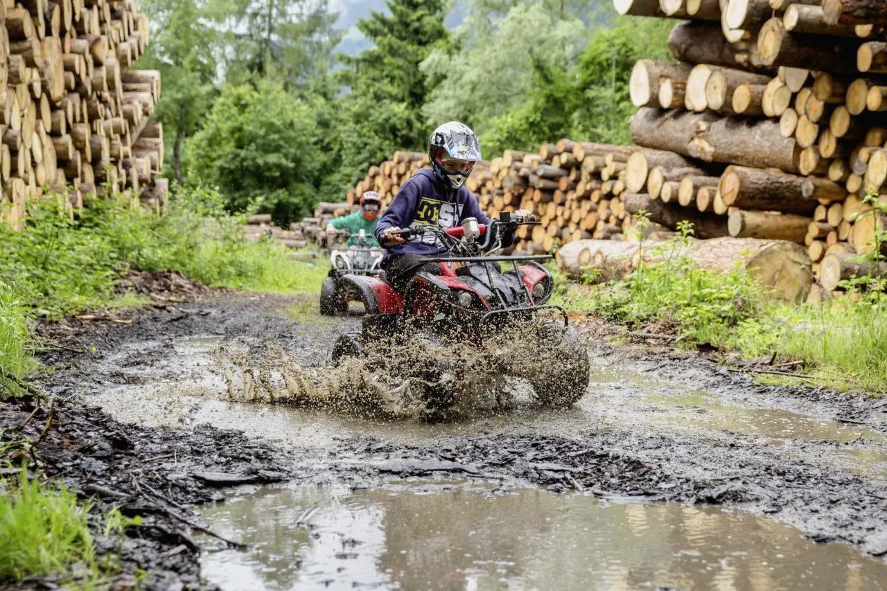 Junge mit Helm fährt Quad durch den Matsch im Quellenhof Luxury Resort Passeier