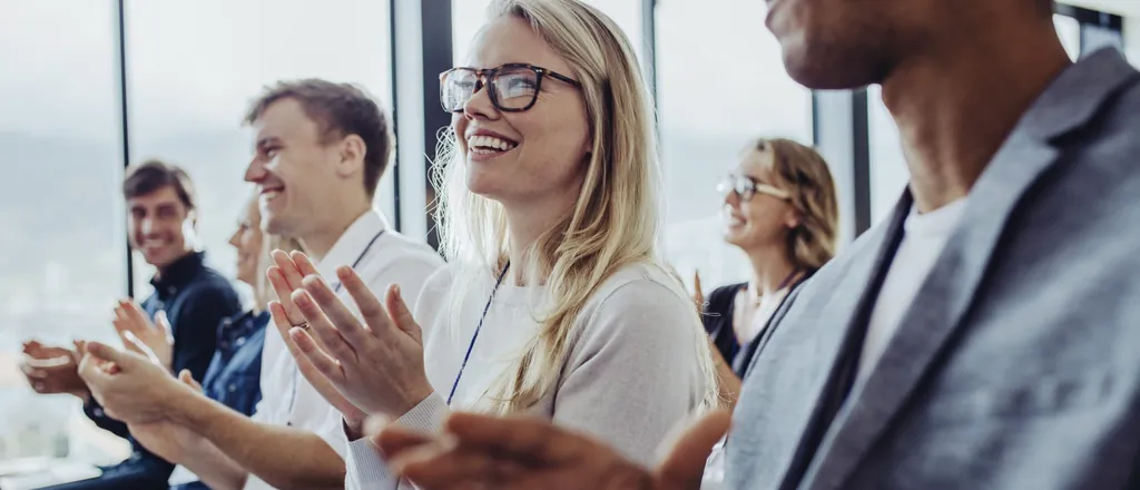 Ein Team von Geschäftsleuten klatscht während einer Tagung in einem Tagungshotel