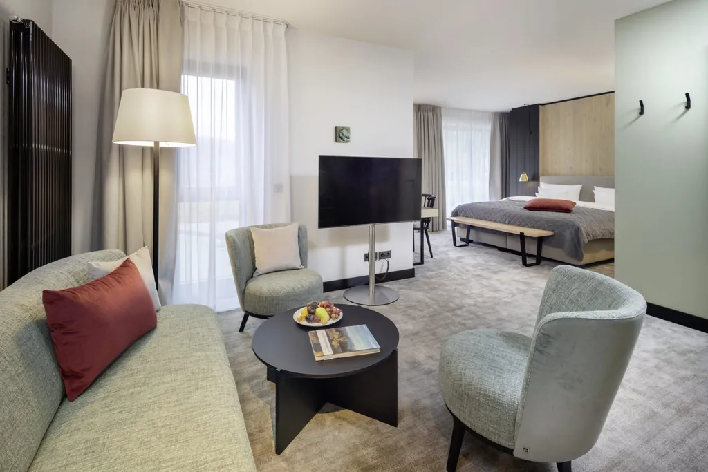 Juniorsuite mit mintfarbenen Sitzmöbeln und heller Holzwand hinter dem Doppelbett im Hotel Engel Obertal