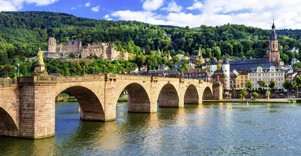 Alte Brücke Heidelberg mit ihren eindrucksvollen Brückentor und bekannten weißen Doppeltürmen. Im Hintergrund die Altstadt sowie das Schloss Heidelburg, das über der Stadt thront.