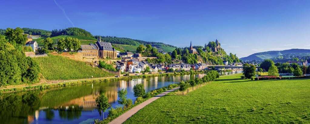 Weinberge, saftige grüne Wiesen und Hügel säumen die Saar an der das Städtchen Saarburg liegt.