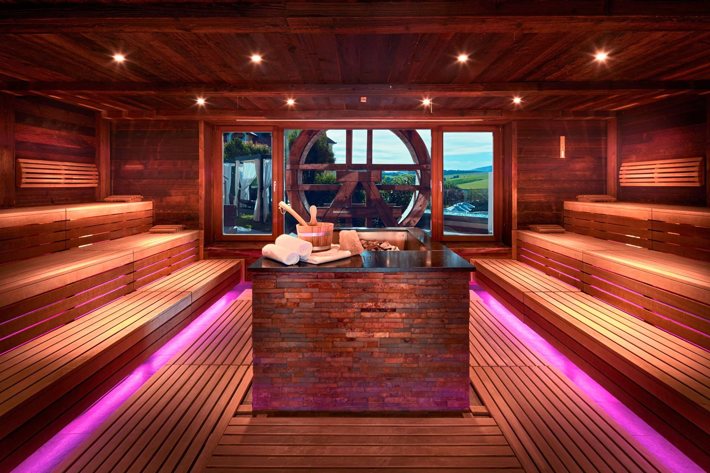 Panoramasauna im Wellnesshotel Jagdhof mit indirekter Beleuchtung unter den Holzb&auml;nken in Pink
