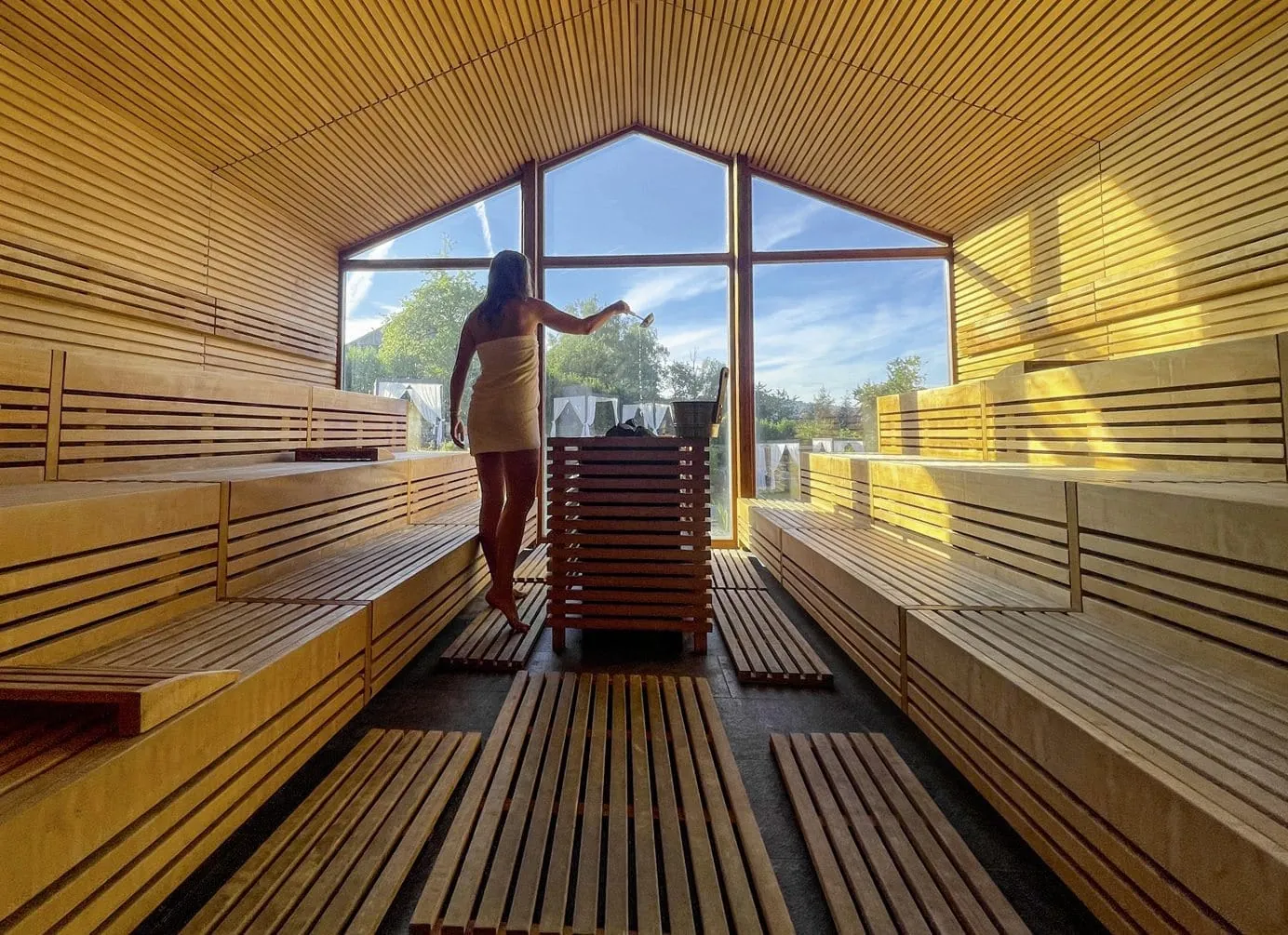 junge Frau mit wei&szlig;em Handtuch umgewickelt, macht in der gro&szlig;z&uuml;gigen Sauna des Ulrichshof gerade einen Aufguss