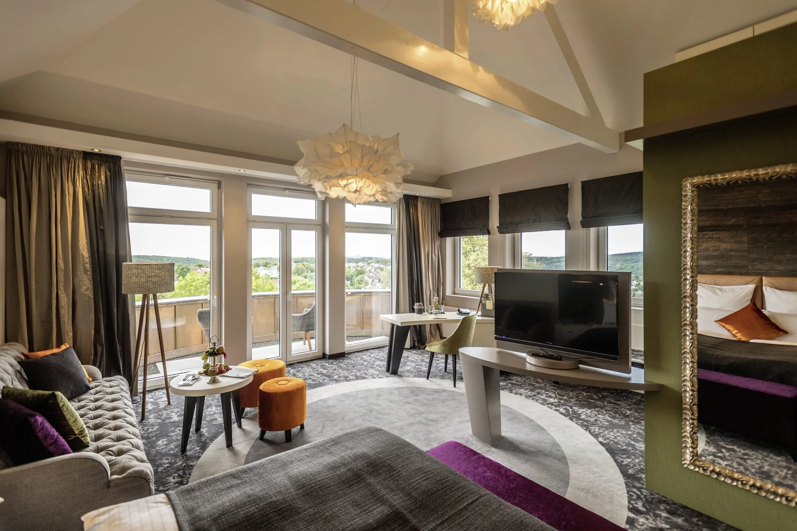 Edle Suite im Hotel Heinz mit Balkon, Sofa, kleinem Tisch und schicken Designerlampen.