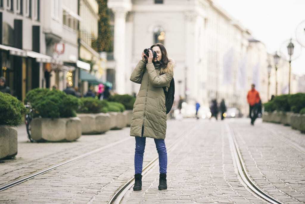 Junge Frau im Wintermantel fotografiert bei ihrem Städtetrip in München