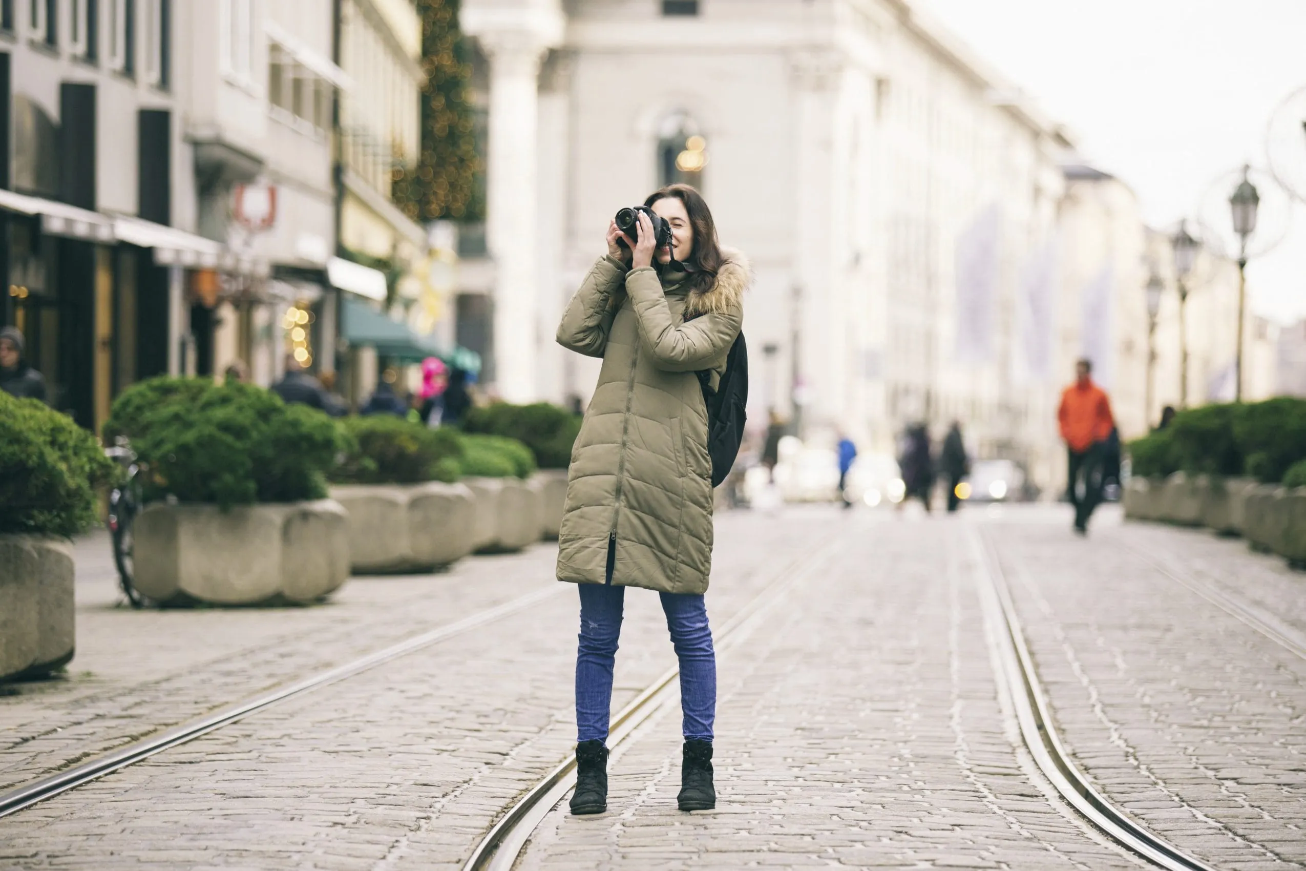Junge Frau im Wintermantel fotografiert bei ihrem Städtetrip in München
