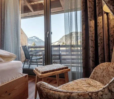 Blick vom großen Ohrensessel im Hotel Oberstdorf auf den Zimmerbalkon mit Bergblick