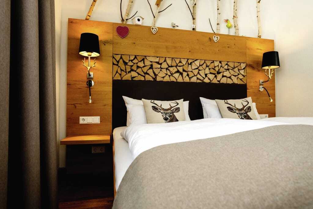 Doppelbett im Waldhotel am Notschreipass mit Hirschkissen und Birkenästen am Kopfende