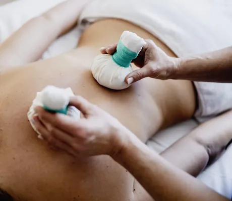 Frau erhält Kräuterstempelmassage mit zwei Stempeln im Waldhotel am Notschreipass