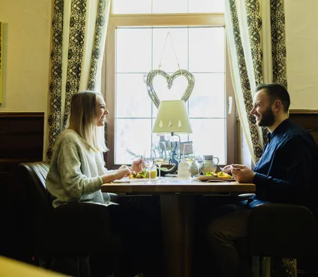 Paar sitzt im Restaurant des Waldhotel am Notschreipass mit Herz am Fenster