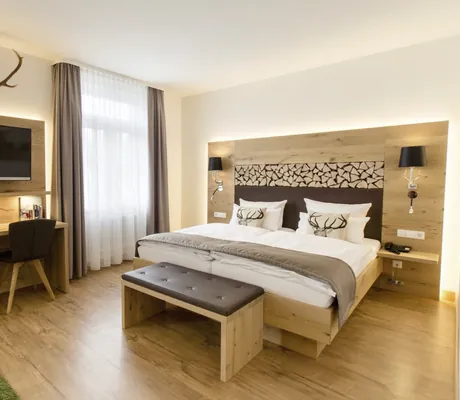 Suite mit Holzboden und Doppelbett mit Hirschkissen im Waldhotel am Notschreipass