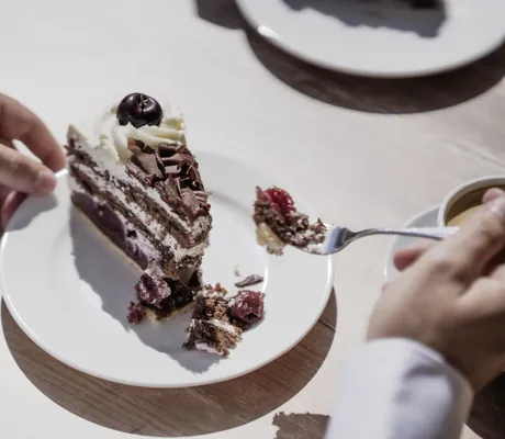 Person isst Schwarzwälder Kirschtorte im Waldhotel am Notschreipass
