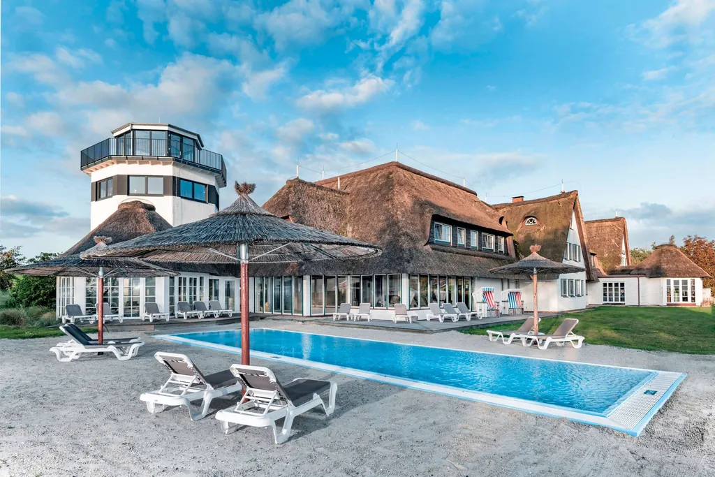 Außenansicht des Adults only-Hotels Lundenbergsand mit Reetdach, Außenpool und kleinem Leuchtturm