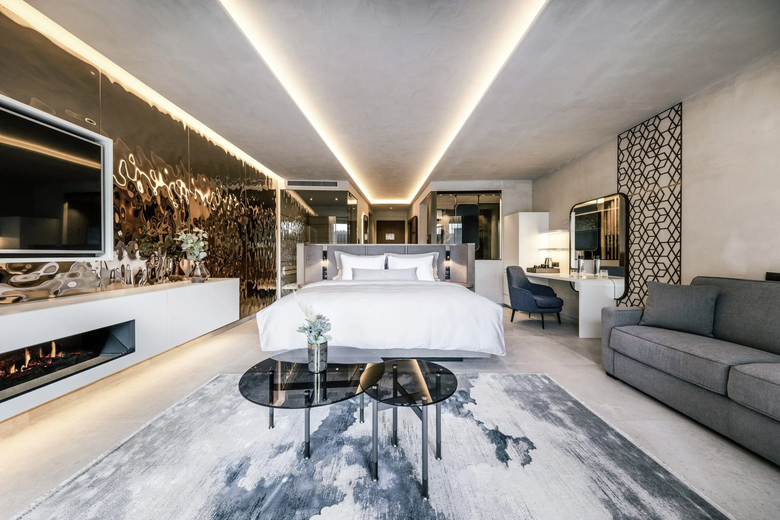 Suite mit gro&szlig;em Kingsizebett, gold-metallischer Wand und blaugemustertem Teppich in der Quellenhof See Lodge