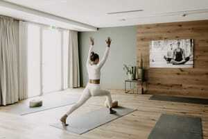 Frau in weißem Sportoutfit macht im Yogaraum des Das Kronthaler eine Yogapose
