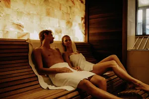 Paar mit weißen Handtüchern liegt auf der Holzliege in der Salzlounge des Das Kronthaler