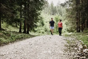 Frau in rotem T-Shirt und Mann in schwarzem T-Shirt wandern durch den Wald rund um Das Kronthaler