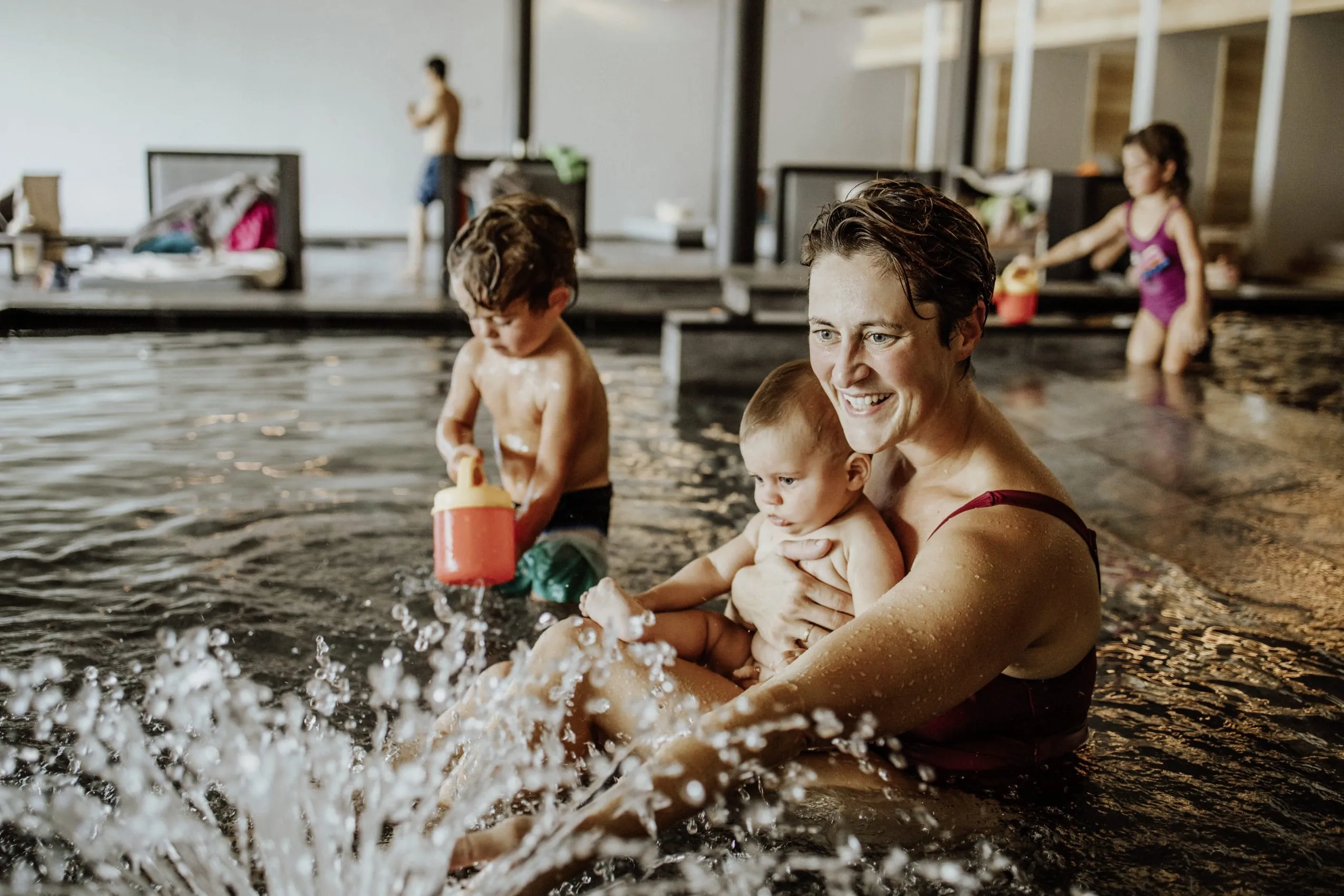 Eine Mutter plantscht mit zwei Kleinkindern im Babybecken des Familienhotels Das Mühlwald