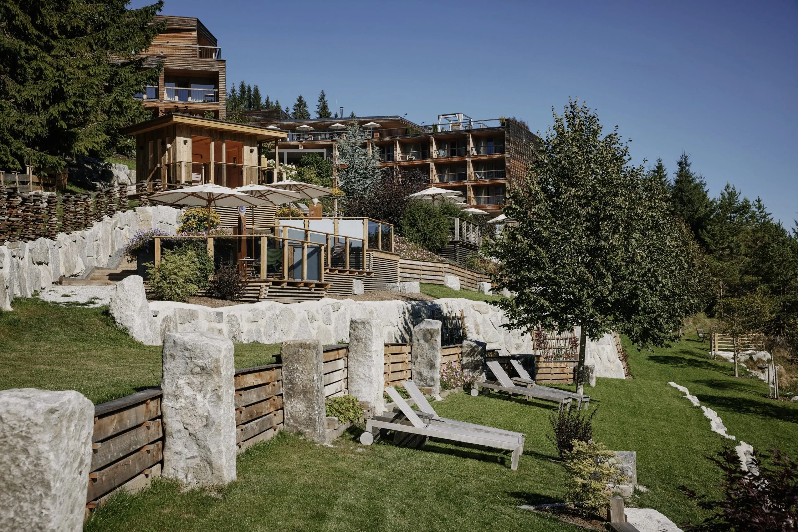 Au&szlig;enansicht des "DAS KRONTHALER" mit Liegewiese am Hang und schicken hellen Steinmauern