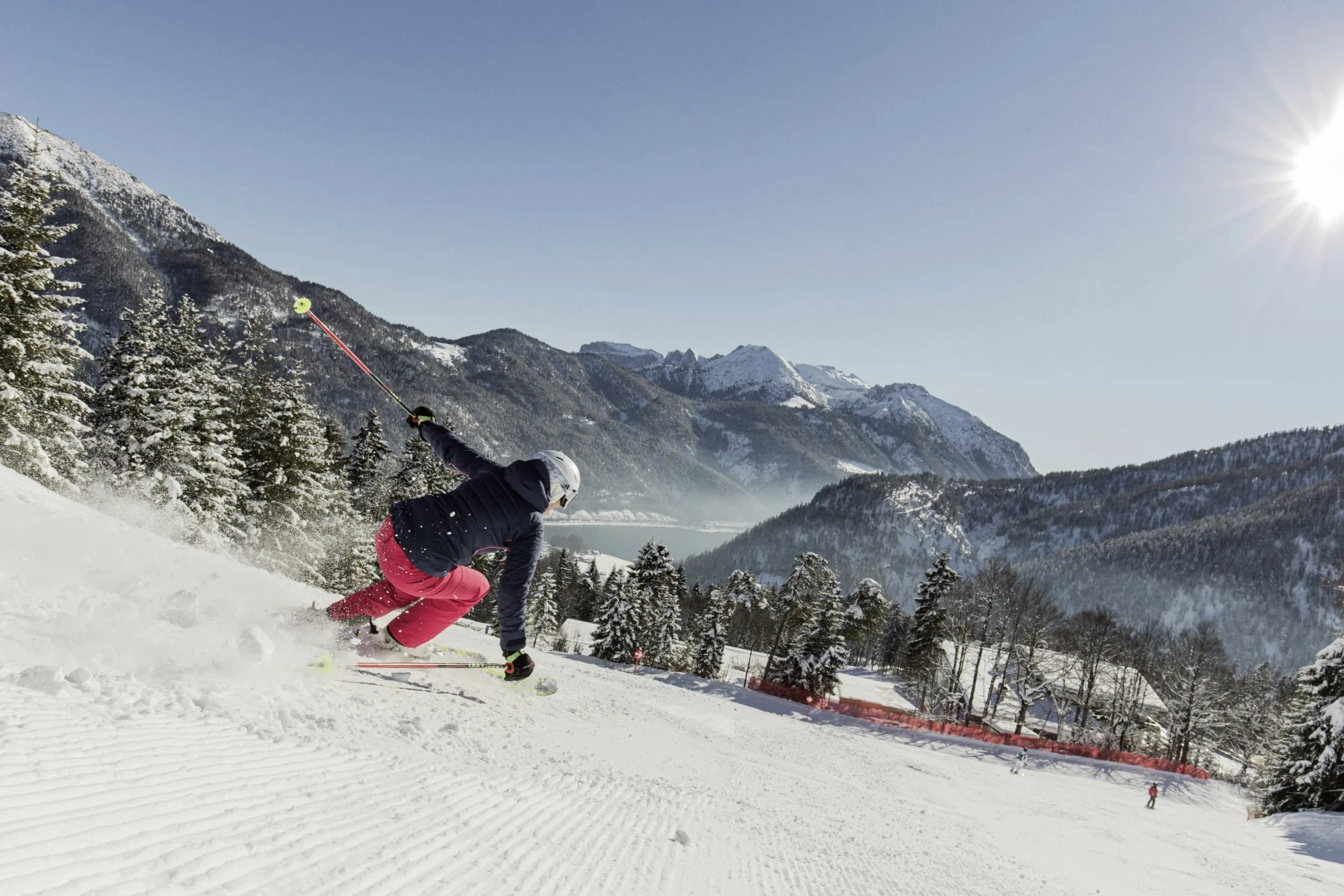 Skigebiet Hochalmlifte Christlum mit Blick auf den Achensee und die umliegende Bergwelt saust eine Skifahrerin die Piste hinunter