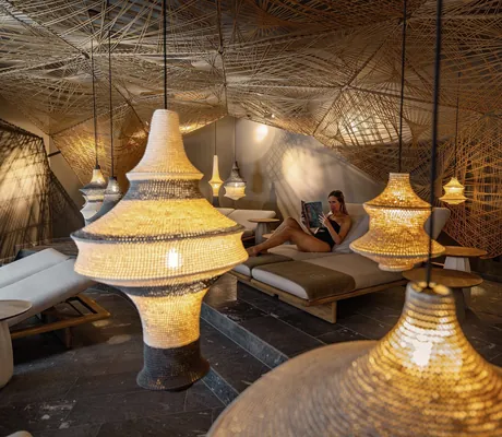 Frau liest Magazin im Ruheraum des Hotel Jungbrunn mit Korbhängelampen und Netzdecke