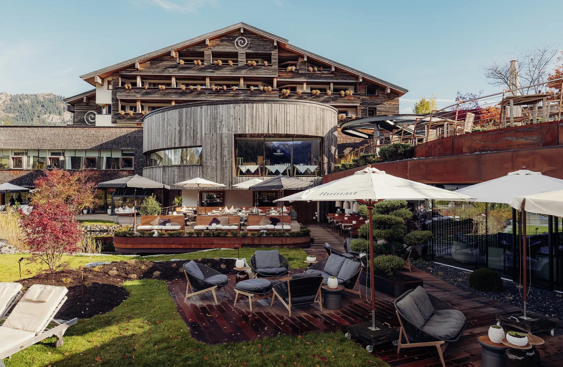 Holzfassade des Hotel Jungbrunn mit rundem Restaurantbau und Blick auf die Terrasse