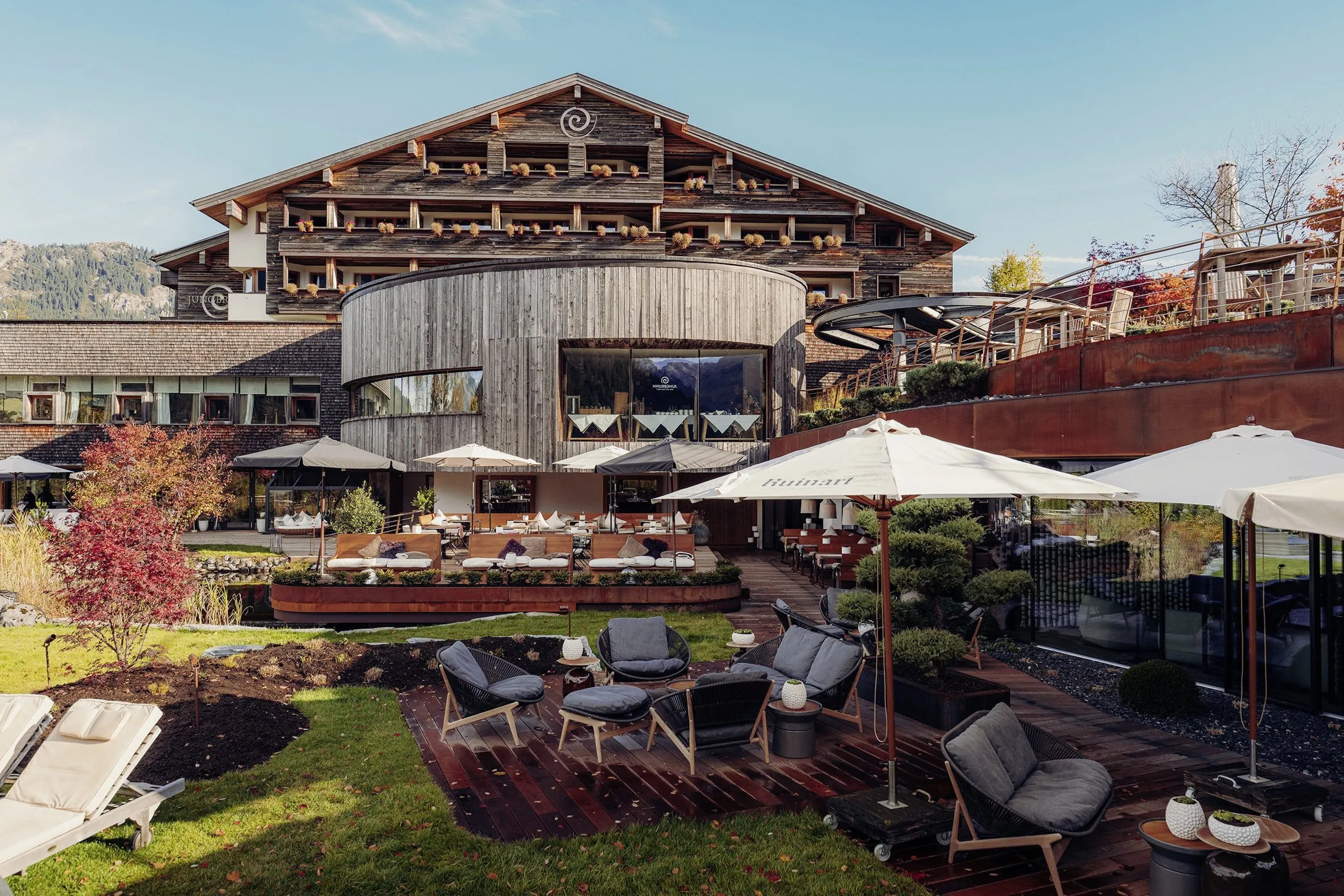 Holzfassade des Hotel Jungbrunn mit rundem Restaurantbau und Blick auf die Terrasse
