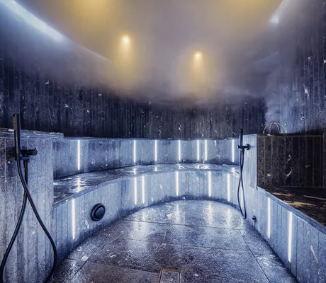 blau beleuchtetes Dampfbad mit Natursteinfliesen im Hotel Jungbrunn