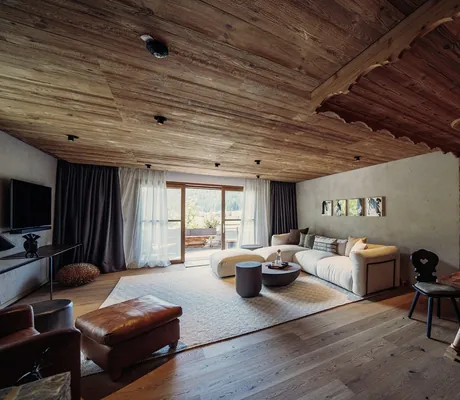 Suite im Hotel Jungbrunn mit großem beigem Relaxsofa und Sitzecke mit traditionellen Möbeln