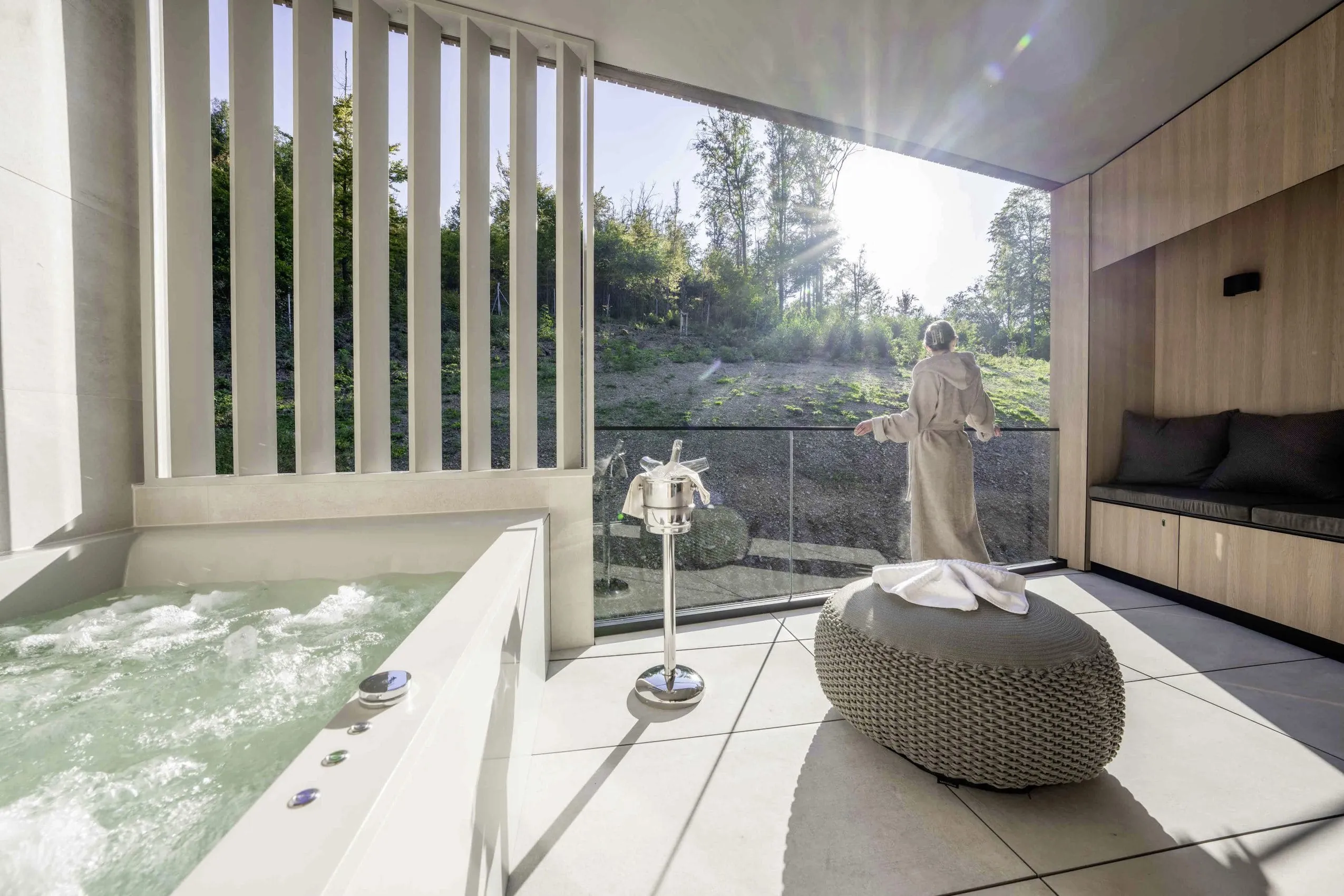 Frau steht im Bademantel auf der Loggia einer Spa Suite im Adults only-Hotel Freiwerk und blickt Richtung Wald