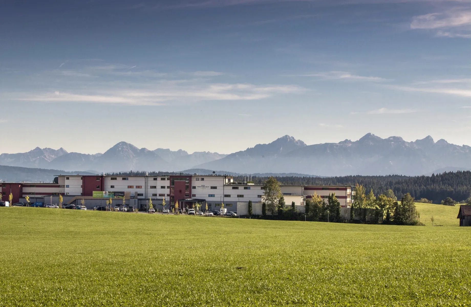 Blick auf das Tagungshotel Das Weitblick Allgäu im Sommer mit Alpenpanorama im Hintergrund