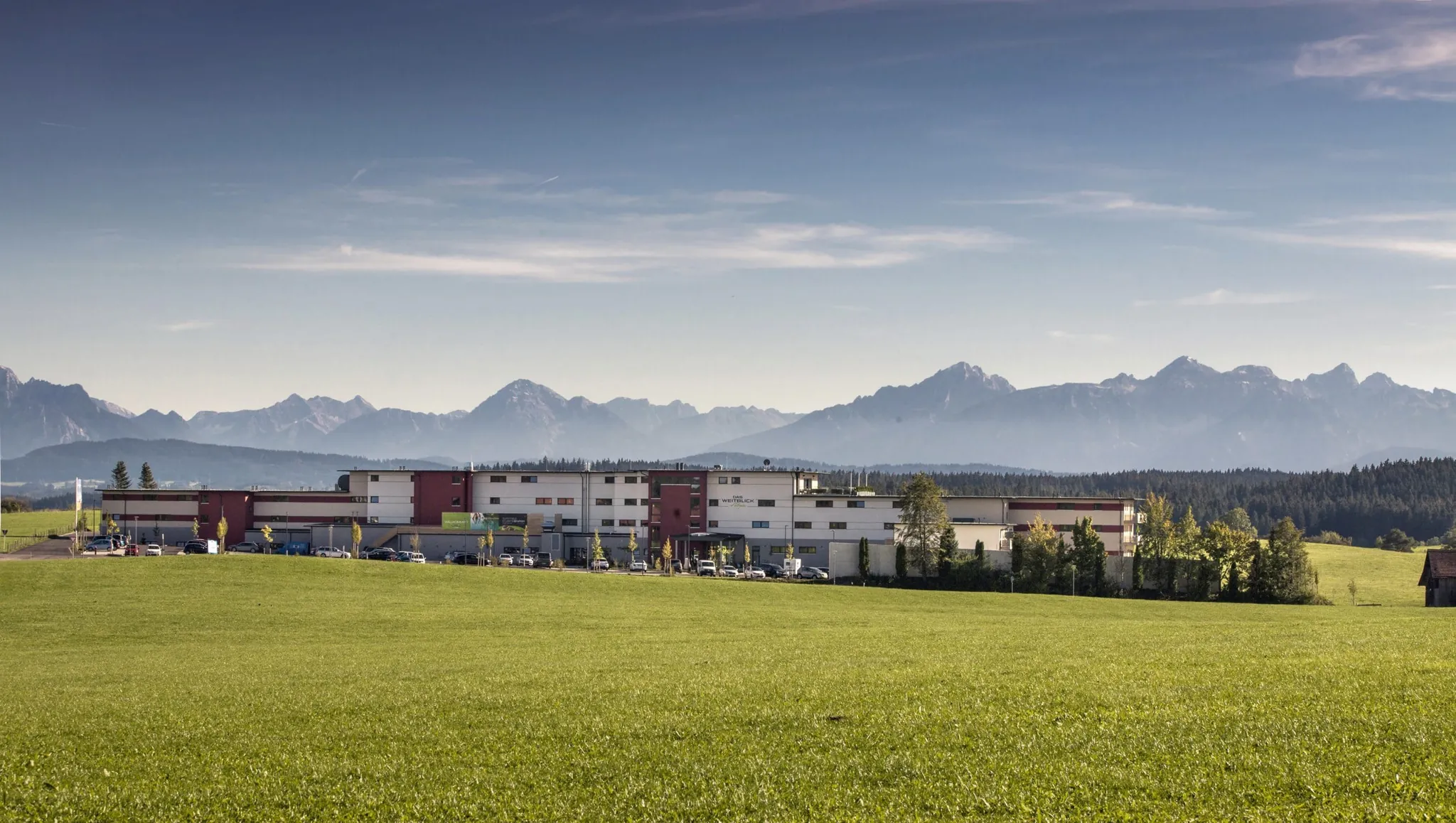 Blick auf das Tagungshotel Das Weitblick Allgäu im Sommer mit Alpenpanorama im Hintergrund