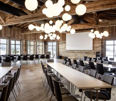 Feststadl mit hölzernem Gebälk, bodentiefen Fenstern und Tischen im Tagungshotel Das Weitblick Allgäu