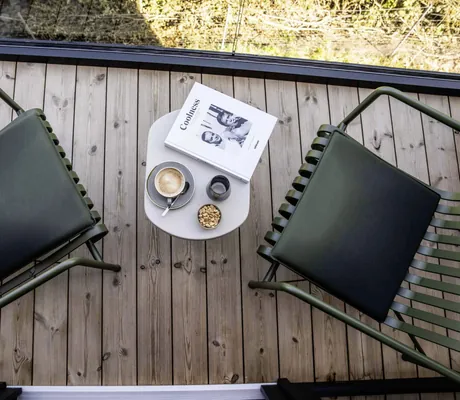 Blick von oben auf den Balkon mit zwei schwarzen Stühlen und Coolness-Buch im Hotel FreiWerk