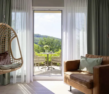 Hänge-Korbsessel und rostrotes Sofa im Hotel FreiWerk mit Blick auf den Balkon