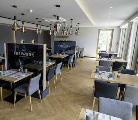 Restaurant im Hotel FreiWerk mit grauen Polsterstühlen und Trennwänden mit Schriftzug