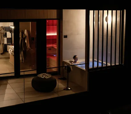 Frau liegt im Whirlpool auf dem Balkon des Hotel FreiWerk bei Nacht