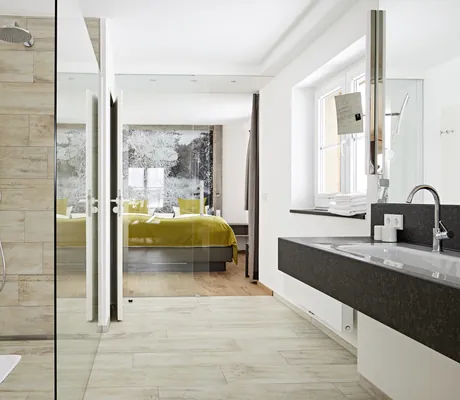 Badezimmer mit Walk-in-Dusche und langem schwarzen Waschtisch in Haubers Naturresort