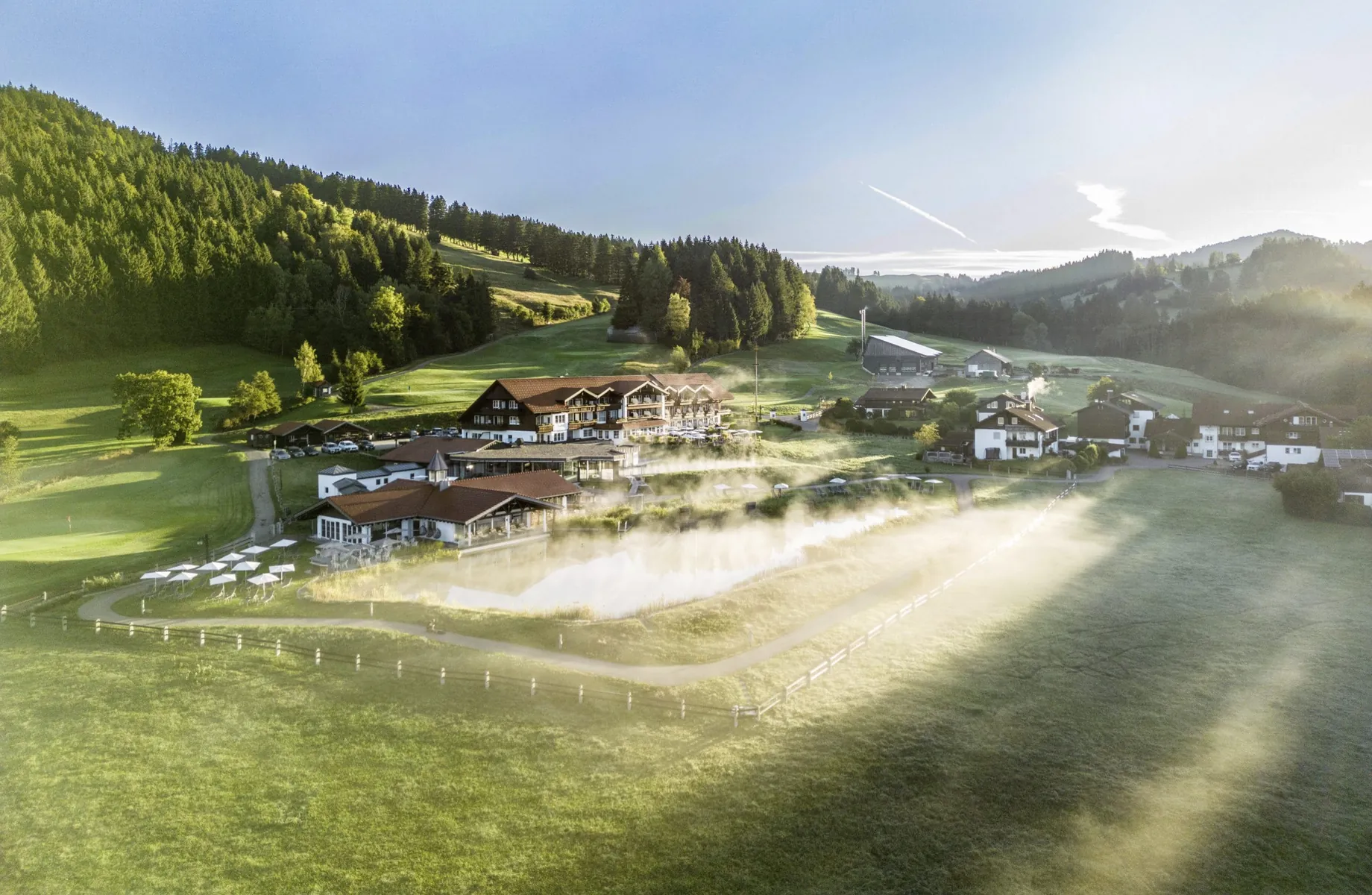 Natursee mit Blick auf das Hotel Haubers Naturresort im Frühnebel